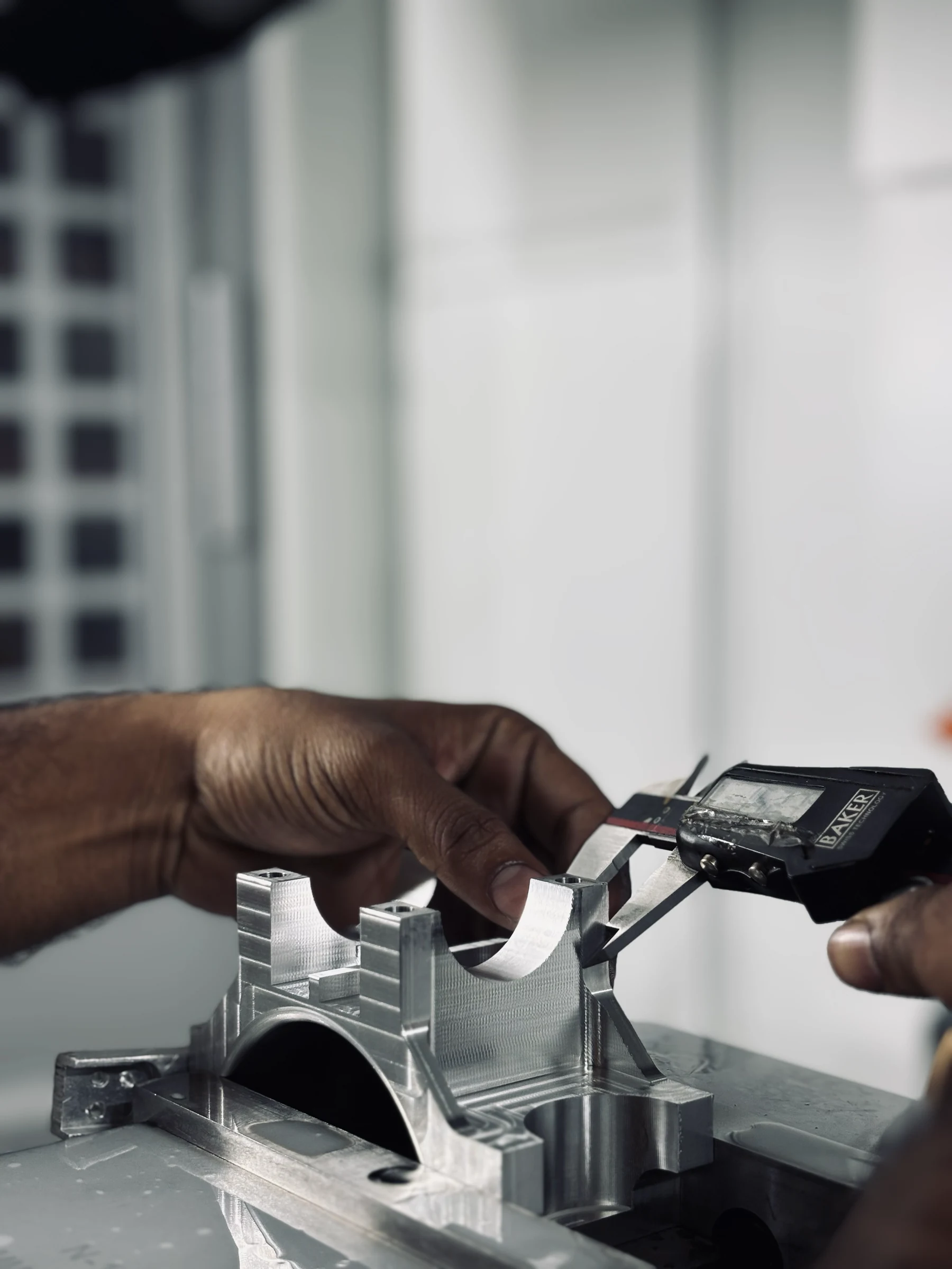 An engineer checking a machined component with digital calipers