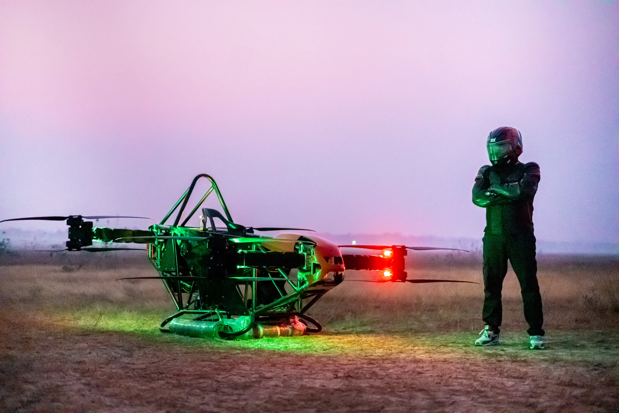 A helmeted pilot standing beside Aer Genesis at dusk